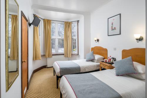 a hotel room with two beds and a mirror at OYO Abbey Hotel, London Shepherd's Bush Market in London