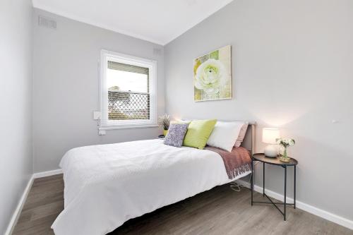 a white bedroom with a bed and a window at Cute and Cosy - events, workers, getaways in Murray Bridge