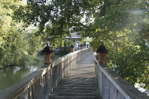a wooden bridge over a river with trees at Les Jardins de Beauval in Saint-Aignan