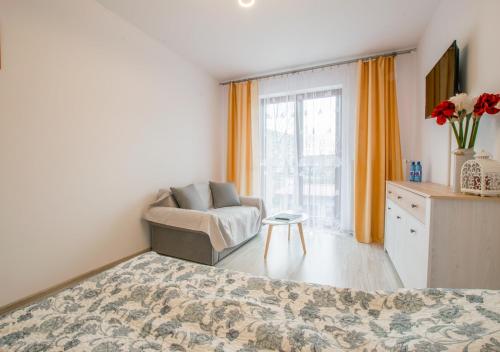a bedroom with a bed and a chair and a window at Central Apartments Goleniow in Goleniów