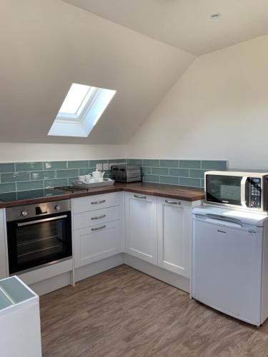 a kitchen with white cabinets and a skylight at The Piggery in Chichester