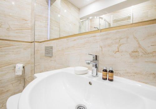 een badkamer met een witte wastafel en een bad bij Central Apartments Goleniow in Goleniów