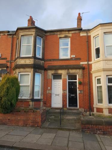 an old brick house with a white door at Jesmond Vale 3 Bedroom Apartment in Newcastle upon Tyne