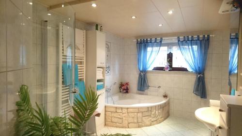 a bathroom with a tub and a shower with blue curtains at "Haus Ulla" in Bad Blankenburg