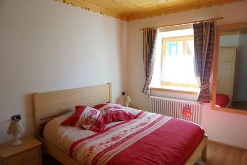 Un dormitorio con una cama con sábanas rojas y una ventana en Lovely House in the Dolomites, en Mazzin