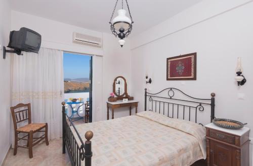a bedroom with a bed and a tv and a window at Yalos rooms in Astypalaia