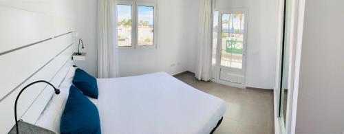 a white bedroom with a bed and two windows at Apartamentos Zalabar in Tías
