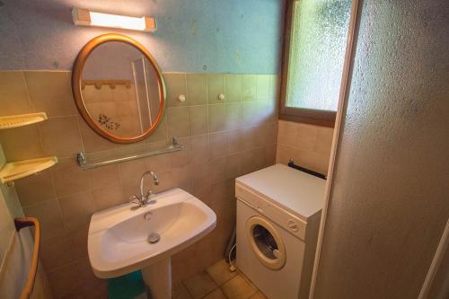 une salle de bain avec un lavabo et un miroir et une machine à laver dans l'établissement Hameau 516, à Aureilhan