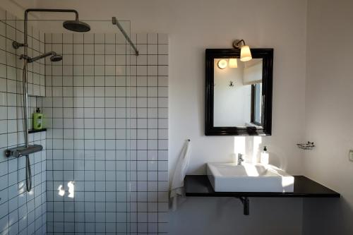 a bathroom with a sink and a mirror and a shower at Casa Verdazul in Tavira
