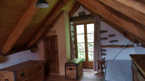 Habitación con altillo con vigas de madera y ventana en Casa Larice, en Mergoscia