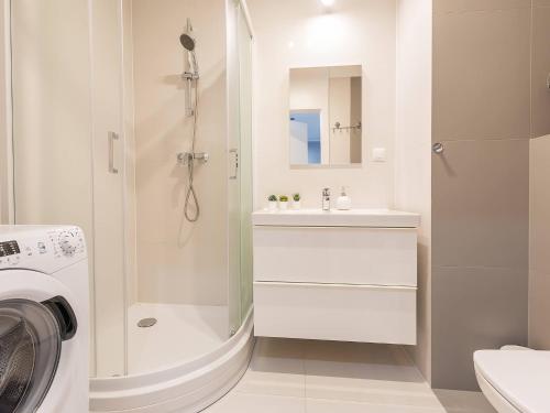 a bathroom with a shower sink and a washing machine at VacationClub – Bliżej Morza Apartament 98 in Kołobrzeg