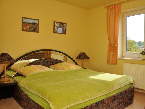 een slaapkamer met een bed met een groene deken erop bij Ferienwohnung Panorama in Schmalkalden
