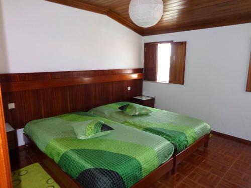 a bedroom with a green bed with a wooden headboard at Quinta da Falca in Nazaré