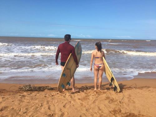 a man and woman standing on the beach with surfboards at Kitnet próximo calcadão Praia Jacaraipe in Serra