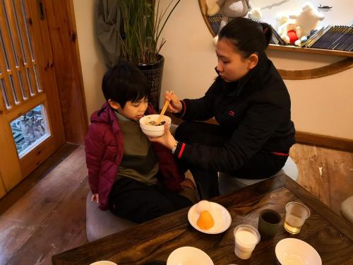 a woman feeding a child a bowl of food at Zhangjiajie National Park Yuelu Homestay in Zhangjiajie