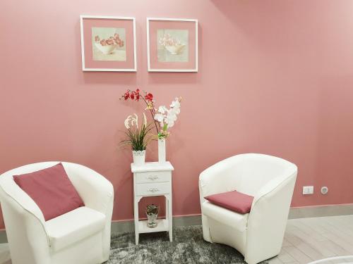 2 weiße Stühle in einem Zimmer mit rosa Wänden in der Unterkunft La Casetta Di Lori Ortigia in Syrakus