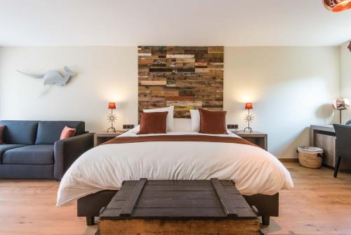 a bedroom with a bed and a blue couch at Koru Hôtel & Private Wellness in Autre-Église