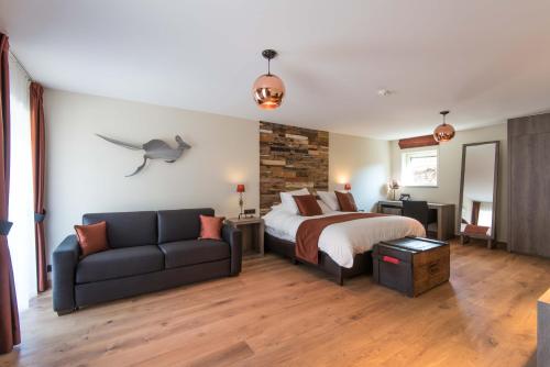 a bedroom with a bed and a couch at Koru Hôtel & Private Wellness in Autre-Église