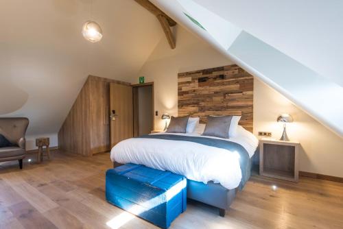 a bedroom with a large bed with a blue suitcase on the floor at Koru Hôtel & Private Wellness in Autre-Église