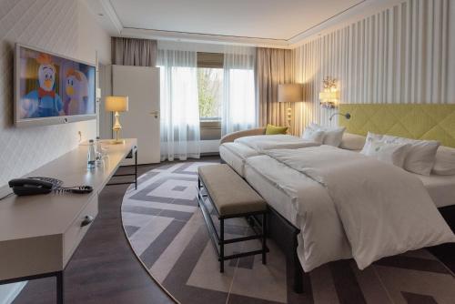 ein Hotelzimmer mit einem großen Bett und einem Schreibtisch in der Unterkunft Insel-Hotel Heilbronn in Heilbronn