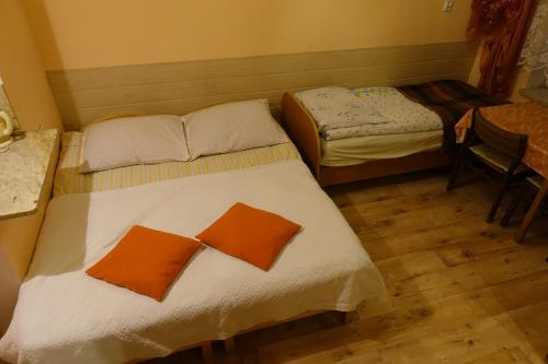 two beds with orange pillows in a room at Pokoje u Szlachty in Szczawnica