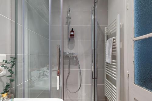 une salle de bain avec une douche avec une porte vitrée dans l'établissement Artisan Lofts courtyard Opéra, à Paris
