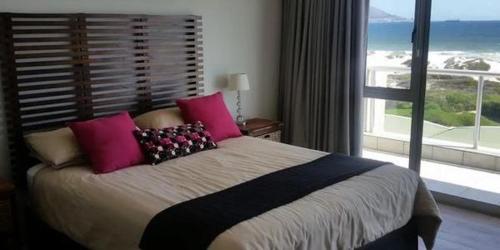 a bedroom with a large bed and a large window at Dolphin Beach Apartment in Table View