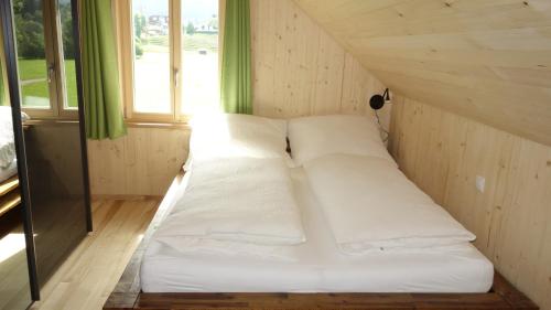 Cama blanca en una habitación pequeña con ventanas en Erwins Ferien-Paradies, en Hörbranz