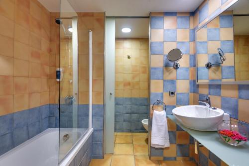 a bathroom with a tub and a sink and a shower at Occidental Playa de Palma in Playa de Palma