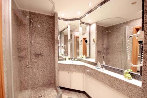 ein Bad mit einer Dusche und einem großen Spiegel in der Unterkunft Dünenpark Binz by Rujana in Binz