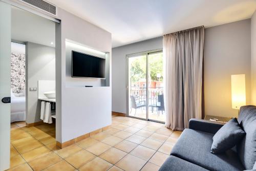 a living room with a couch and a desk with a television at Occidental Playa de Palma in Playa de Palma