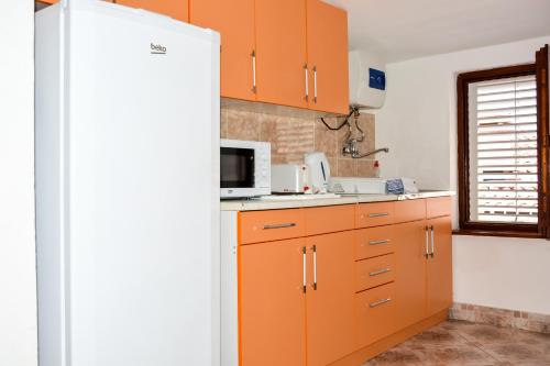 a kitchen with orange cabinets and a microwave at Apartments Minja S in Petrovac na Moru