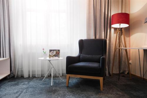 a chair and a lamp in a room with curtains at Hotel Restaurant Höldrichsmühle in Hinterbrühl