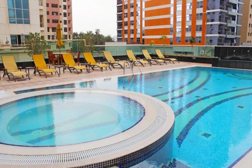 a large swimming pool with chairs on a building at Dunes Hotel Apartment Oud Metha, Bur Dubai in Dubai