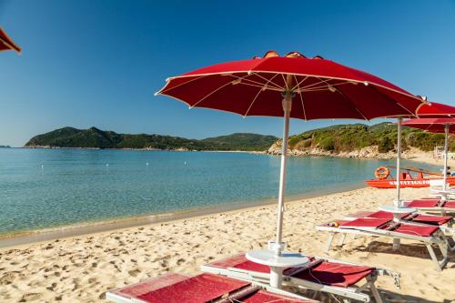 a group of chairs and an umbrella on a beach at Sant'Elmo Beach Hotel in Castiadas