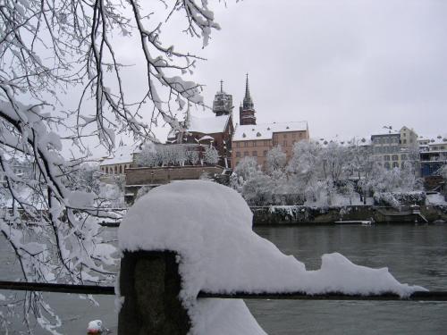 a bridge covered in snow next to a river with buildings at Exclusive Central Apartment in Basel
