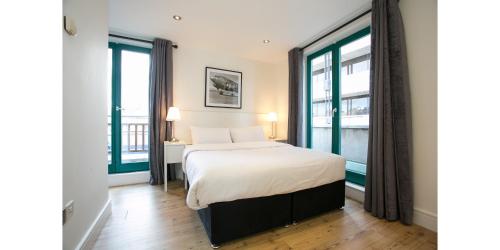 ダブリンにあるTemple Bar District Apartmentsのベッドと2つの大きな窓がある寝室
