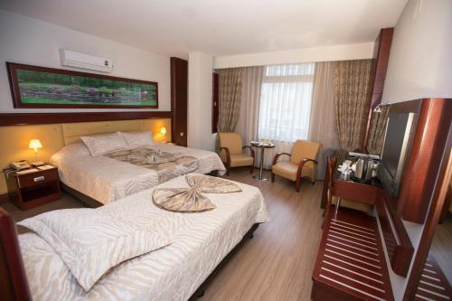 メルスィンにあるMersin Oteliのベッド2台、薄型テレビが備わるホテルルームです。