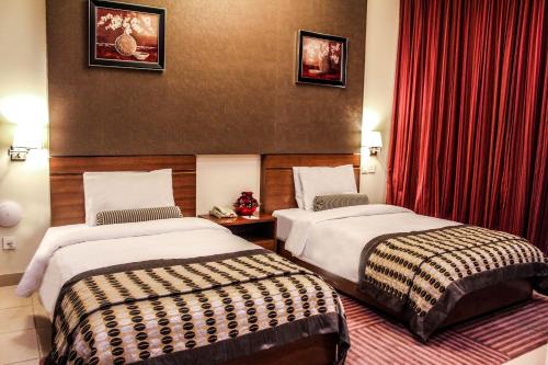 two beds in a hotel room with red curtains at Dunes Hotel Apartment Oud Metha, Bur Dubai in Dubai