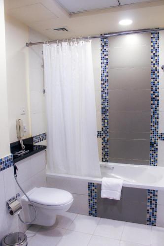 a bathroom with a toilet and a bath tub with a shower curtain at Dunes Hotel Apartment Oud Metha, Bur Dubai in Dubai