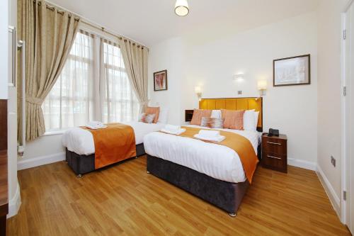 a hotel room with two beds and a window at Imperial Guest House Ltd. in Hounslow