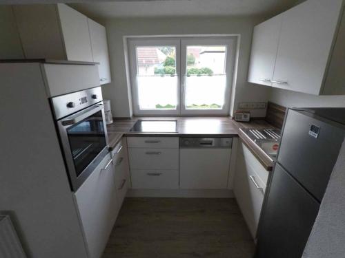 a small kitchen with white cabinets and a window at Ferienwohnung am Schloss in Königstein in Kürmreuth
