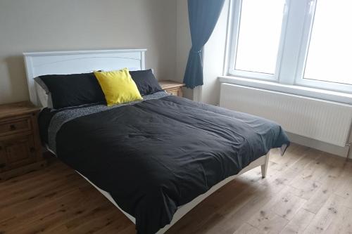 a bed with a black comforter and a yellow pillow at Murrayfield Spacious 1 bedroom apartment in Edinburgh