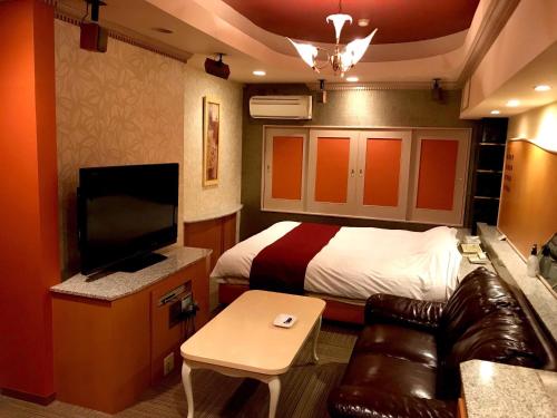 a bedroom with a bed and a couch and a tv at Hotel Patio Ise (Adult Only) in Ise