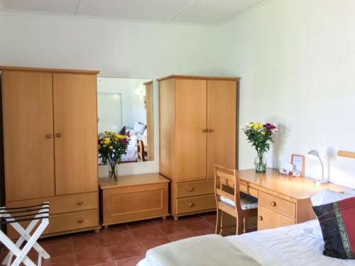 a bedroom with wooden cabinets and a desk and a bed at Howards End Manor B&B in Cape Town