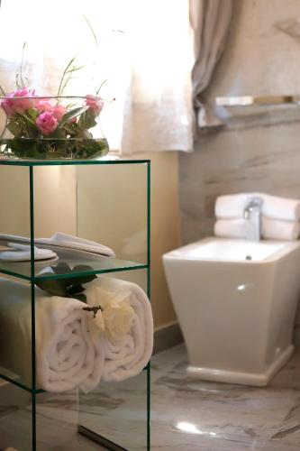 a bathroom with a toilet and a glass table with flowers at Residenza D'Epoca -Santa Caterina in Pisa