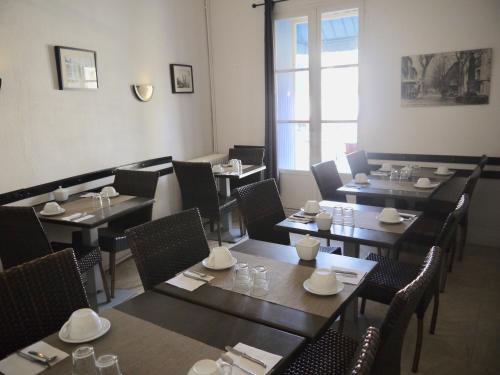 une salle à manger avec des tables et des chaises ainsi qu'une fenêtre dans l'établissement Hotel De La Poste, à Ganges