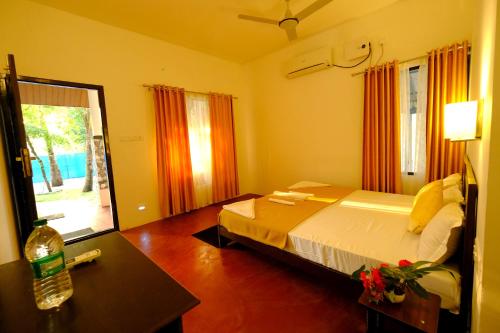 a bedroom with a bed and a table and a window at Marari Lotus Beach Villa in Mararikulam