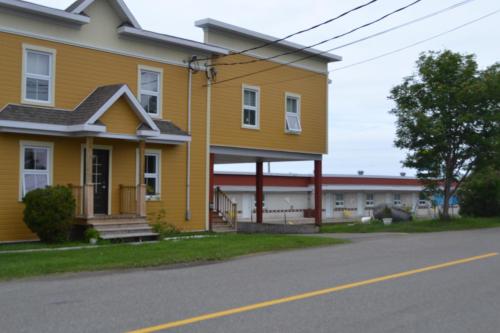 a yellow house on the side of a street at Motel Rimouski in Rimouski