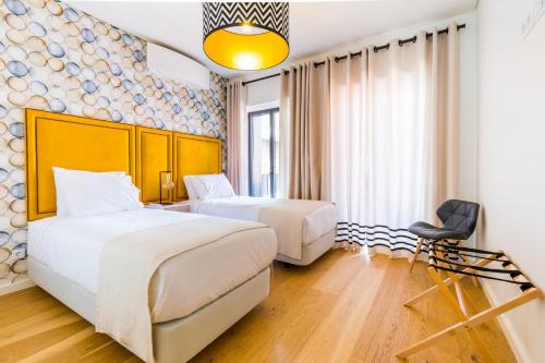 une chambre d'hôtel avec deux lits et une chaise dans l'établissement ALTIDO Bairro Alto 2-BR Apartment with Large Terrace, à Lisbonne
